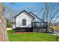 Side view of modern renovated home with a black and white trim, outdoor deck, and green lawn at 3482 Atlanta St, Atlanta, GA 30337
