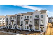 Beautiful townhome with a painted brick exterior, black trim, and a manicured front yard under a blue sky at 516 Healy Dr # 69, Cumming, GA 30040