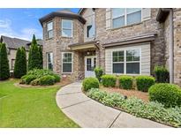 Charming brick home with lush landscaping and curved walkway leading to the covered front entrance at 2196 Abbott Dr, Buford, GA 30519