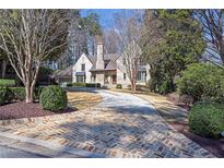 Charming Tudor-style home featuring a circular driveway and meticulously landscaped front yard at 333 Pineland Nw Rd, Atlanta, GA 30342
