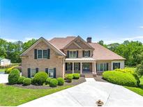 Stunning brick home featuring manicured landscaping, a covered front porch, and a circular driveway with a water fountain at 714 Billings Farm Ln, Canton, GA 30115