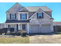 Charming two-story home with brick facade, attached two-car garage, and inviting front porch at 227 Happy Trl, Locust Grove, GA 30248