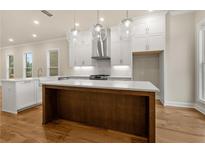 Bright kitchen with stainless steel appliances, wooden island, and elegant globe pendant lights at 169 Wards Crossing Way # 125, Johns Creek, GA 30022
