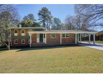 Charming two-story home with brick facade, covered entry, and spacious front yard on a sunny day at 6875 Sunny Brook Ln, Atlanta, GA 30328