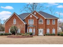 Charming two-story brick home featuring a manicured lawn, mature landscaping, and welcoming front entrance at 1715 Branchwood Ct, Powder Springs, GA 30127