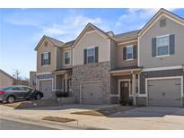 Charming townhome exterior featuring a mix of siding and brick with individual garages and well-kept landscaping at 6928 Zaniah Rd, Atlanta, GA 30331