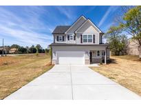 Two-story home showcasing a gray exterior, with a two car garage and long concrete driveway at 7477 Caribou Trl, Riverdale, GA 30296