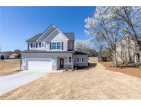 Charming two-story home with gray siding, manicured lawn, and an attached two-car garage at 7477 Caribou Trl, Riverdale, GA 30296