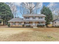 Charming two-story home with brick and siding, shutters, a covered front porch, and a well-manicured front yard at 4481 Buckingham Cir, Decatur, GA 30035