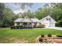 Charming home featuring a metal roof, inviting front porch, landscaping, and a two-car garage with basketball hoop at 281 Laney Dr, Locust Grove, GA 30248