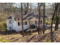 Charming white cottage-style home nestled among trees with black shutters and a cozy front porch at 581 Scott Mill Rd, Canton, GA 30114