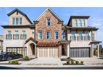 Attractive townhome row features stone and brick exterior, two-car garages, and manicured landscaping at 202 Via Lucca, Woodstock, GA 30188