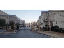 Charming street view of townhomes behind a black gated entrance and well-maintained landscaping at 2021 Towneship Trl, Roswell, GA 30075