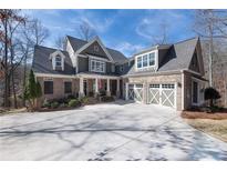 Beautiful brick home featuring a spacious driveway and a charming three-car garage with decorative doors at 6880 Nantucket Cv, Cumming, GA 30041