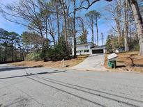 Inviting two-story home featuring a charming white exterior, a spacious driveway, and mature trees at 1211 Golden Cir, Lilburn, GA 30047