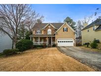 Charming two-story home featuring a stone facade, tan siding, a manicured lawn and an attached two-car garage at 2164 Caneridge Sw Dr, Marietta, GA 30064