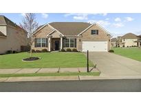Charming single Gathering home featuring a lush green lawn and attached two car garage at 7330 Olivia View Ct, Cumming, GA 30028