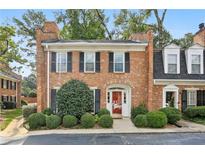 Charming brick townhome featuring a manicured lawn with lush greenery, black shutters and a welcoming red front door at 7 Newport Nw Pl, Atlanta, GA 30318