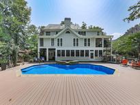 A backyard view of the home showcasing a sparkling pool with a wooden deck and lovely landscaping at 1012 Jubilee Way, Powder Springs, GA 30127