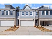 Attractive townhome with a light gray exterior, white garage doors, and coordinated landscaping for curb appeal at 1024 Rose Dr, Marietta, GA 30060