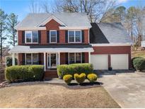 Charming brick home featuring a manicured front yard with lush green hedges and a two-car garage at 3595 Ansley Park Dr, Suwanee, GA 30024