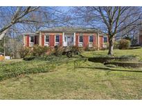 Charming brick home with red shutters and a well-manicured front yard featuring mature landscaping at 663 Foxcroft Circle Se, Marietta, GA 30067