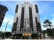 Exterior view of a modern high-rise condo building featuring balconies, trees, and manicured landscaping at 3481 Lakeside Ne Dr # 1705, Atlanta, GA 30326