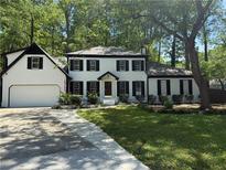 Charming two-story home featuring a well-maintained front yard, dark shutters, and attached garage at 3900 Millwood Lane Nw, Lilburn, GA 30047