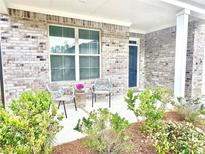 Inviting front porch featuring brick facade and seating area with two chairs and side table at 325 Caledonia Ct, Peachtree City, GA 30269