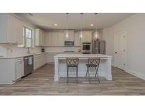Bright, modern kitchen with white cabinets, stainless steel appliances, and an island with seating at 325 Caledonia Ct, Peachtree City, GA 30269