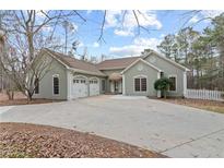 Charming single-story home with a spacious driveway and three-car garage nestled among mature trees at 398 Picketts Xing, Acworth, GA 30101