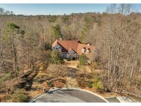 Stunning exterior view of a house with a circular driveway and a lush, wooded surrounding at 3460 Mansions Pkwy, Berkeley Lake, GA 30096