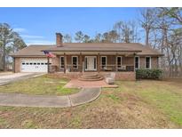 Charming brick home with a covered front porch and attached garage, showcasing curb appeal at 6890 Cedar Mountain Rd, Douglasville, GA 30134