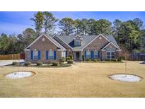 Charming brick home with blue shutters, manicured lawn, and mature trees at 1832 Millstone Mnr, Conyers, GA 30013