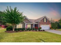 Charming brick home with a manicured lawn, mature tree, and an inviting two-car garage at 1119 Simonton Glen Way, Lawrenceville, GA 30045