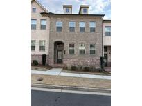 Charming brick townhome with three stories, arched entryway, and neat landscaping at 262 Commons Avenue, Woodstock, GA 30188