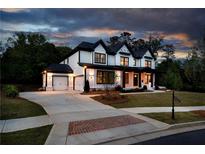 Beautiful two-story home with a three-car garage, a well-manicured lawn, and a brick-laden driveway at 320 Dodd Ln, Alpharetta, GA 30005