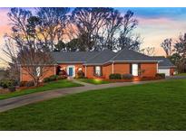 Charming brick home with manicured lawn, complemented by mature trees and inviting curb appeal at 12195 Mountain Laurel Dr, Roswell, GA 30075