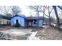 Exterior view of a blue one-story home with a small porch and overgrown landscaping at 1429 Funston Se Ave, Atlanta, GA 30315