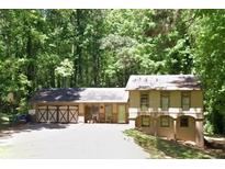 Two-story home featuring a spacious multi-car garage, surrounded by lush greenery and mature trees at 5531 Four Winds Sw Dr, Lilburn, GA 30047