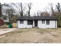 Charming one-story home with a freshly painted white brick exterior and a well-maintained front lawn at 2945 Catalina Dr, Decatur, GA 30032