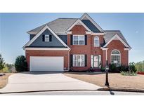 Charming two-story brick home with a well-maintained front yard and attached two-car garage on a sunny day at 5915 Vintage Oaks Pass, Mableton, GA 30126