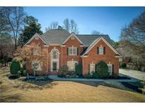 Beautiful brick two-story home with a manicured front lawn and mature trees, offering classic curb appeal at 900 Great Rissington Way, Alpharetta, GA 30022