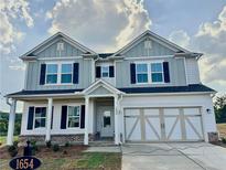 Beautiful two-story home featuring a two-car garage, classic shutters, and a covered front porch at 1654 Tide Mill Rd, Cumming, GA 30040