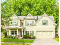 Charming two-story home featuring light green siding, green shutters, and a well-manicured lawn at 4273 Creekrun Cir, Buford, GA 30519