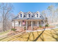 Charming two-story home featuring a welcoming porch and landscaped front yard and American flag at 170 River Cove Rdg, Social Circle, GA 30025