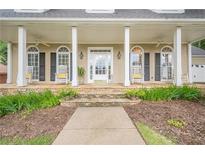 Inviting front porch with white columns, rocking chairs, and stone steps leading to the entrance at 6360 Brookline Ct, Cumming, GA 30040