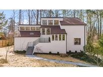Modern home exterior featuring a white facade, dark trim, and a landscaped front yard at 2626 Shadow Woods Ne Cir, Marietta, GA 30062