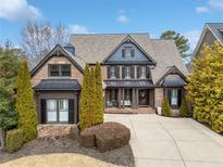 Charming brick home with manicured landscaping, dark shutters, and inviting covered front porch at 7010 Wakehurst Pl, Cumming, GA 30040