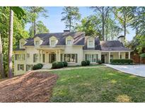 Elegant two-story home with painted brick, dormer windows, mature trees and manicured landscaping, offering great curb appeal at 1025 Dawn View Nw Ln, Atlanta, GA 30327